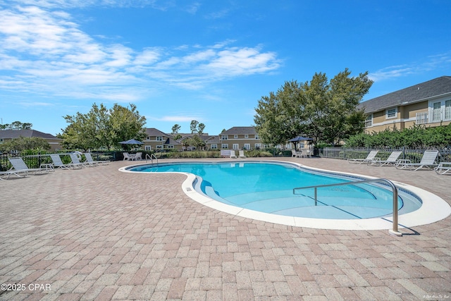 community pool with fence, a patio area, a gazebo, and a residential view