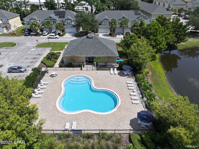community pool featuring fence, a residential view, and a water view
