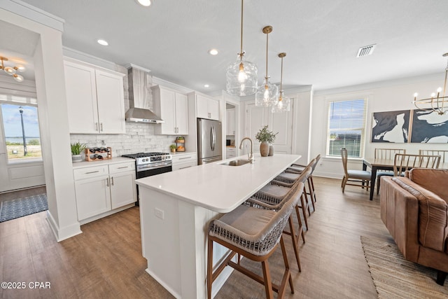 1009 N Discovery Loop, Panama City, FL 32405 - kitchen with appliances with stainless steel finishes, wall chimney exhaust hood, a chandelier, a sink, and wood finished floors
