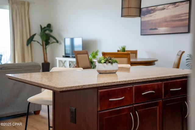 kitchen with wood finished floors, open floor plan, a center island, and a kitchen bar