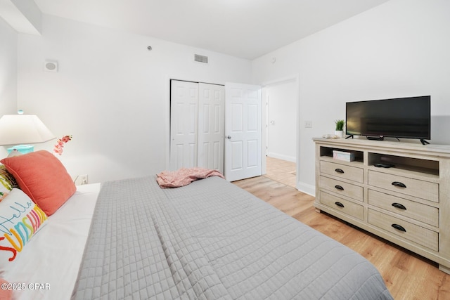 bedroom with light wood-style floors, a closet, and baseboards