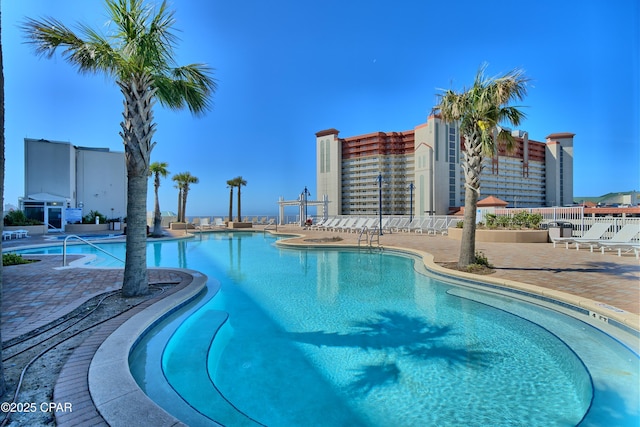 community pool with a patio area and fence