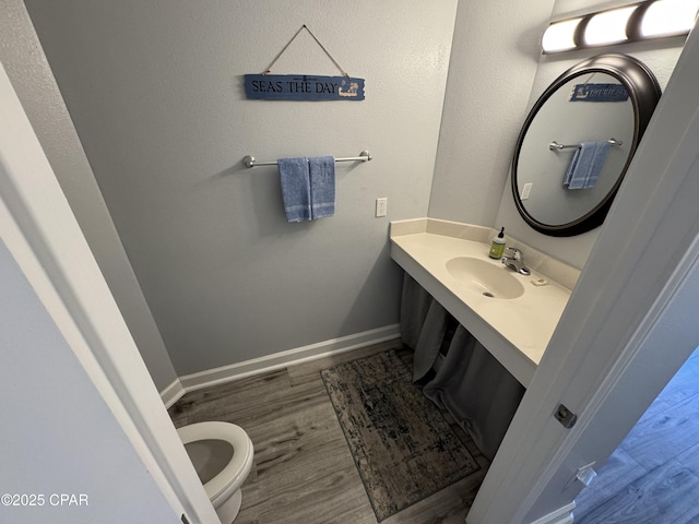 9900 S Thomas Dr Unit 2023, Panama City Beach, FL 32408 - half bathroom with vanity, wood finished floors, baseboards, and toilet