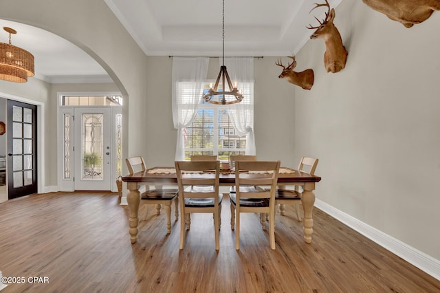 1104 Zephyr, Panama City, FL 32404 - dining space featuring arched walkways, wood finished floors, baseboards, a raised ceiling, and ornamental molding