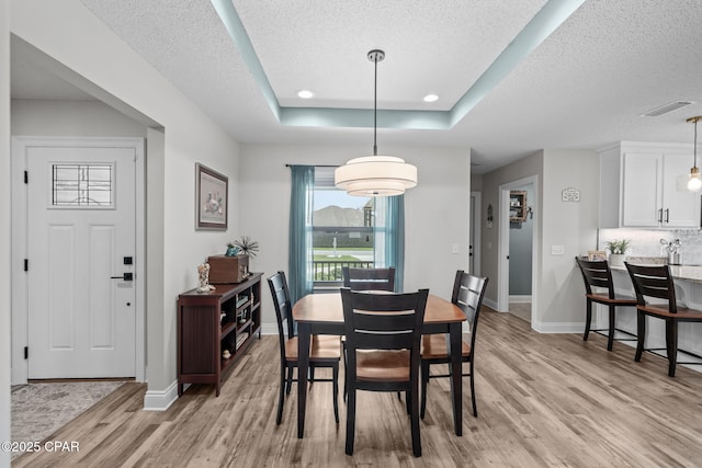 4724 Bylsma Cir, Panama City, FL 32404 - dining area featuring light wood finished floors, baseboards, a textured ceiling, and a raised ceiling