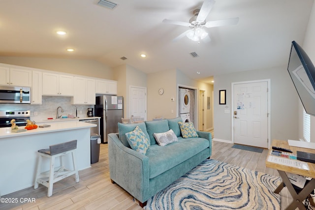 6128 Loquat St, Panama City Beach, FL 32408 - living room featuring stacked washer / drying machine, light wood finished floors, lofted ceiling, and ceiling fan