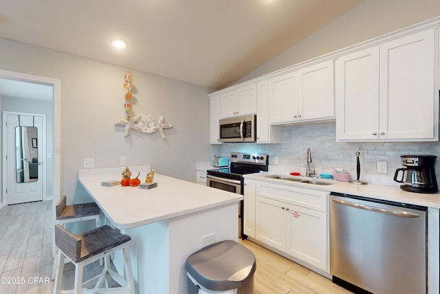 6128 Loquat St, Panama City Beach, FL 32408 - kitchen featuring stainless steel appliances, a breakfast bar area, a sink, decorative backsplash, and white cabinetry