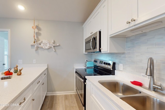 6128 Loquat St, Panama City Beach, FL 32408 - kitchen featuring stainless steel appliances, a sink, decorative backsplash, light wood-style flooring, and white cabinetry