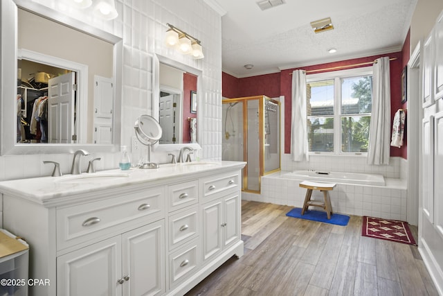 16532 SW Mimosa St, Blountstown, FL 32424 - bathroom featuring a shower stall, wood finished floors, a garden tub, double vanity, and a textured ceiling