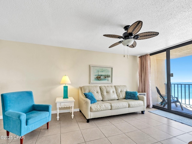 6505 Thomas Dr Unit 1009B, Panama City Beach, FL 32408 - living room featuring floor to ceiling windows, a textured ceiling, ceiling fan, light tile patterned floors, and a water view