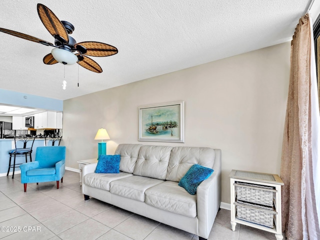 6505 Thomas Dr Unit 1009B, Panama City Beach, FL 32408 - living room featuring a textured ceiling, a ceiling fan, light tile patterned flooring, and baseboards