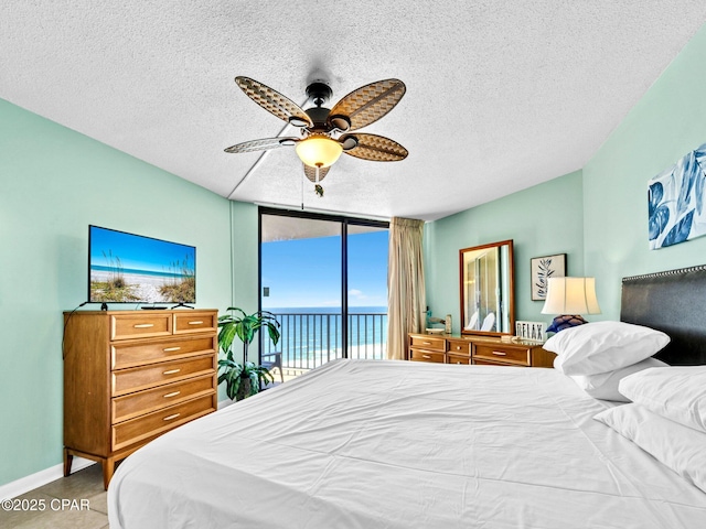 6505 Thomas Dr Unit 1009B, Panama City Beach, FL 32408 - bedroom with access to outside, a textured ceiling, ceiling fan, baseboards, and a wall of windows