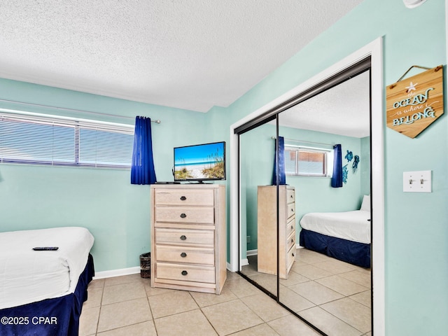 6505 Thomas Dr Unit 1009B, Panama City Beach, FL 32408 - bedroom with a closet, light tile patterned flooring, a textured ceiling, and baseboards