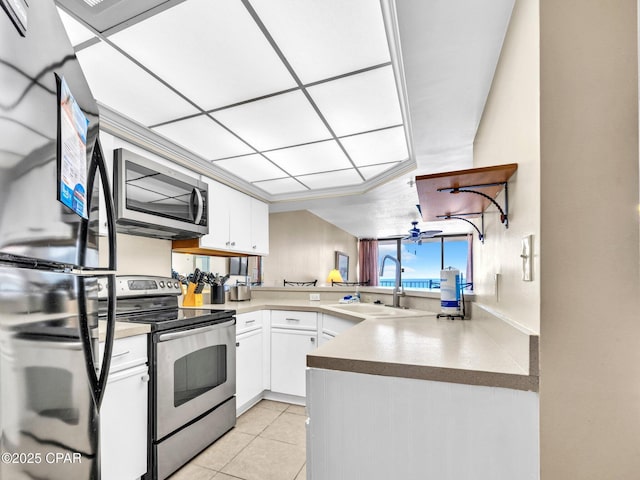 6505 Thomas Dr Unit 1009B, Panama City Beach, FL 32408 - kitchen with appliances with stainless steel finishes, a sink, white cabinetry, light tile patterned floors, and a peninsula
