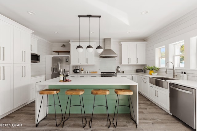 98 Shirah St, Destin, FL 32541 - kitchen with wall chimney exhaust hood, appliances with stainless steel finishes, a kitchen island, white cabinetry, and recessed lighting