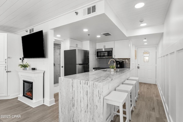 9850 S Thomas Dr Unit 1112E, Panama City Beach, FL 32408 - kitchen featuring stainless steel appliances, light wood-style floors, a kitchen bar, a peninsula, and white cabinetry