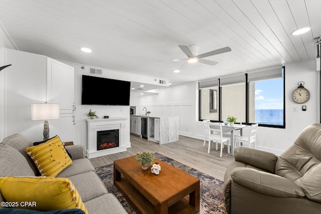 9850 S Thomas Dr Unit 1112E, Panama City Beach, FL 32408 - living area featuring beverage cooler, ceiling fan, a glass covered fireplace, light wood finished floors, and wooden ceiling