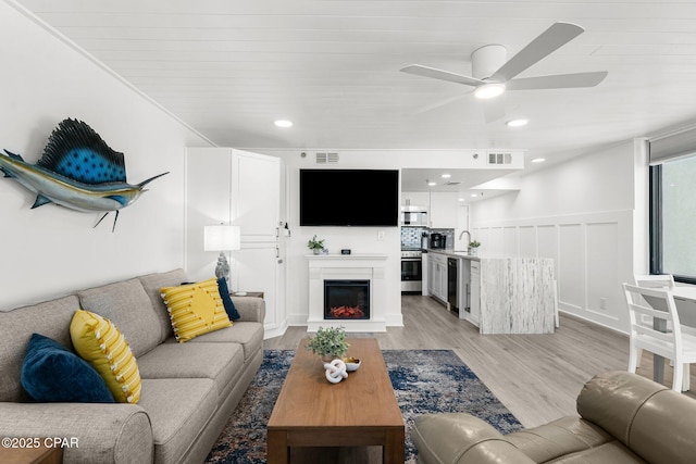 9850 S Thomas Dr Unit 1112E, Panama City Beach, FL 32408 - living room with ceiling fan, wine cooler, a warm lit fireplace, light wood-type flooring, and wainscoting