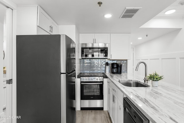 9850 S Thomas Dr Unit 1112E, Panama City Beach, FL 32408 - kitchen with stainless steel appliances, a sink, light stone countertops, white cabinetry, and backsplash