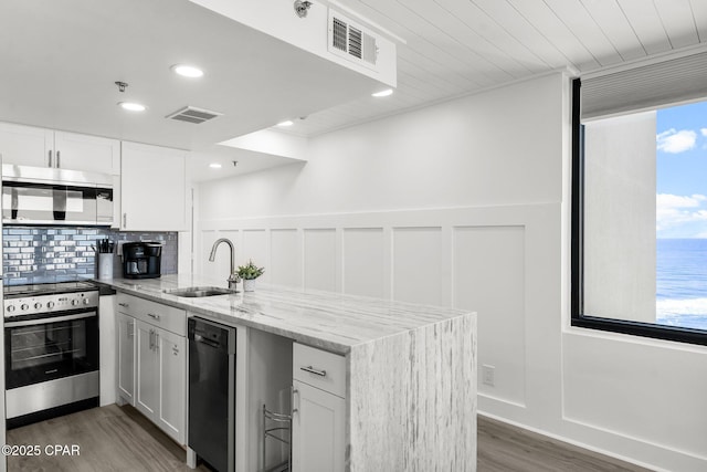 9850 S Thomas Dr Unit 1112E, Panama City Beach, FL 32408 - kitchen featuring stainless steel appliances, a sink, a peninsula, wood finished floors, and white cabinets