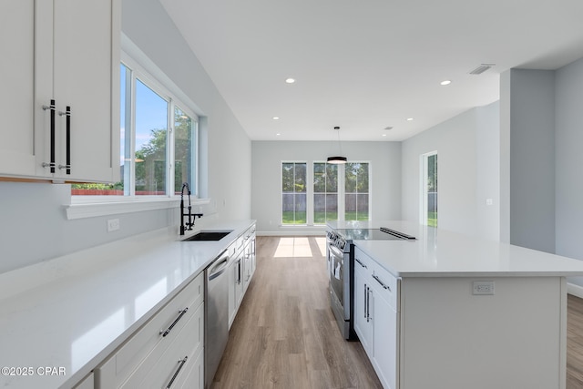 12809 Merial Green Way, Southport, FL 32409 - kitchen with a sink, appliances with stainless steel finishes, light wood-style floors, white cabinets, and light countertops