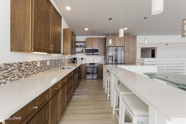 13826 Front Beach Rd, Panama City Beach, FL 32413 - kitchen featuring stainless steel appliances, a sink, open shelves, a kitchen breakfast bar, and light wood finished floors