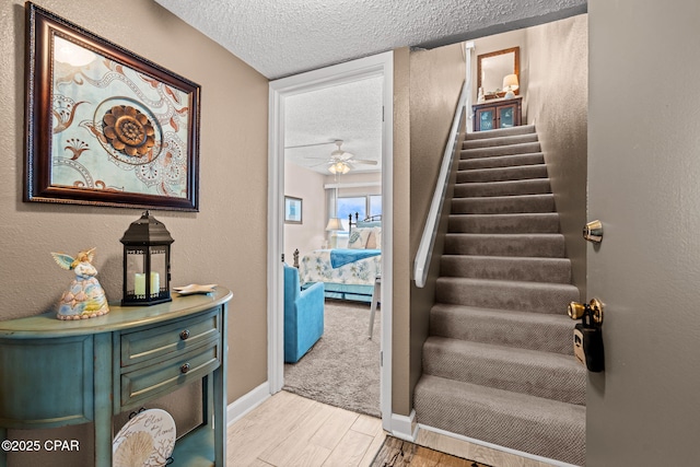 23223 Front Beach Rd Unit A509, Panama City Beach, FL 32413 - stairs featuring a textured ceiling, baseboards, a ceiling fan, wood finished floors, and a textured wall