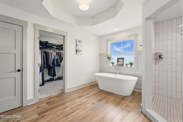 3928 Sandpine Way, Panama City, FL 32404 - bathroom with wood finished floors, a tile shower, a freestanding tub, a spacious closet, and a raised ceiling