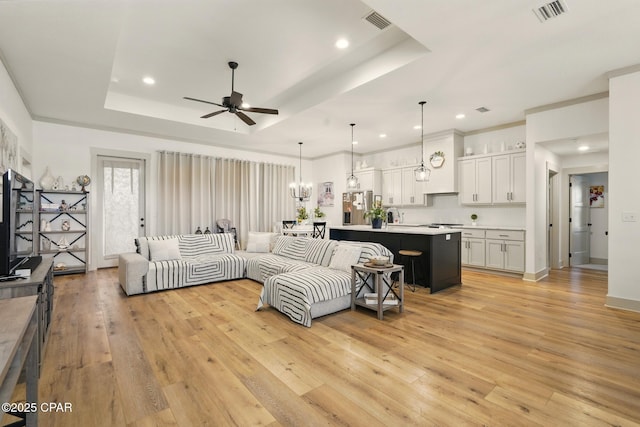 3928 Sandpine Way, Panama City, FL 32404 - living room featuring a raised ceiling, a ceiling fan, recessed lighting, light wood-style floors, and a chandelier