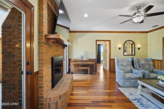 18562 Lois Fowler Rd, Blountstown, FL 32424 - living area featuring a wainscoted wall, wood finished floors, a ceiling fan, a brick fireplace, and crown molding