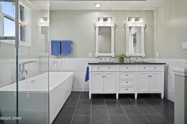 18562 Lois Fowler Rd, Blountstown, FL 32424 - full bathroom featuring tile walls, tile patterned floors, a freestanding tub, double vanity, and a wainscoted wall