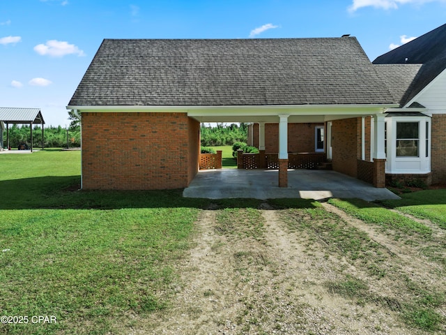 18562 Lois Fowler Rd, Blountstown, FL 32424 - view of home's exterior featuring driveway, a yard, brick siding, a shingled roof, and a patio area