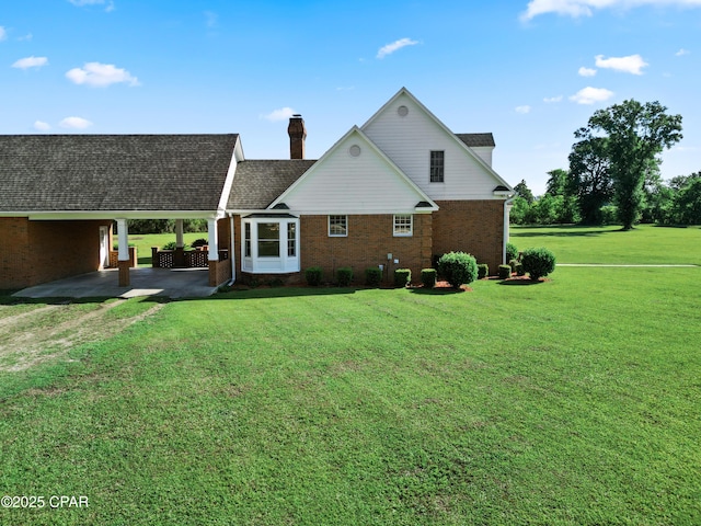 18562 Lois Fowler Rd, Blountstown, FL 32424 - rear view of property with brick siding, a yard, a chimney, an attached carport, and driveway