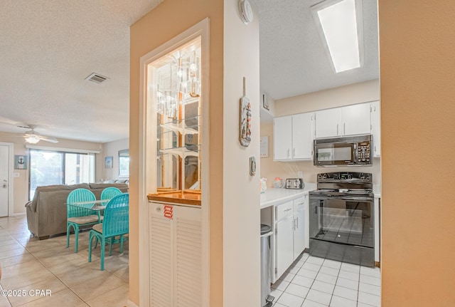 17620 Front Beach Rd Unit 2V, Panama City Beach, FL 32413 - kitchen with black appliances, light tile patterned floors, a textured ceiling, white cabinetry, and light countertops