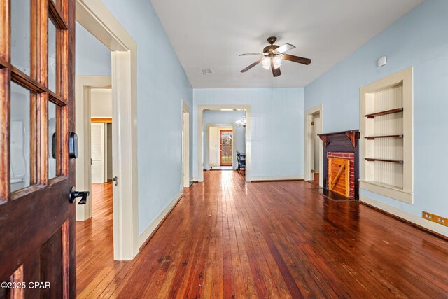 208 N E Ave, Panama City, FL 32401 - unfurnished living room featuring a ceiling fan, hardwood / wood-style flooring, a fireplace, baseboards, and built in shelves