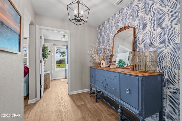 160 James Way, Southport, FL 32409 - hall featuring wallpapered walls, light wood-style floors, a chandelier, baseboards, and an accent wall