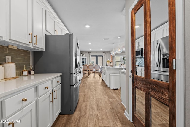 160 James Way, Southport, FL 32409 - kitchen with appliances with stainless steel finishes, light wood-type flooring, white cabinets, light countertops, and decorative backsplash