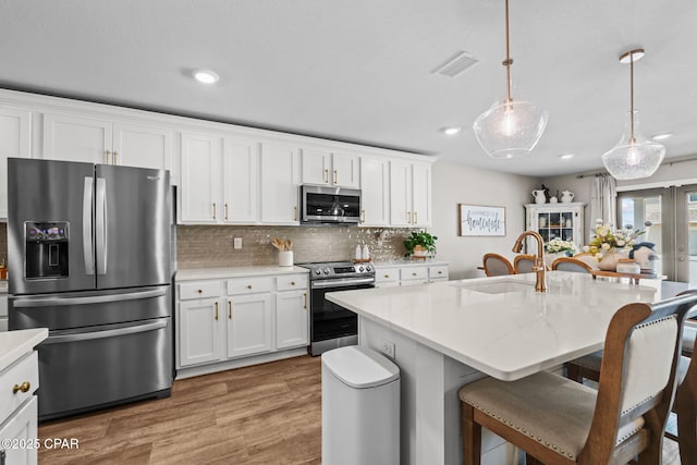 160 James Way, Southport, FL 32409 - kitchen featuring appliances with stainless steel finishes, a sink, a kitchen breakfast bar, tasteful backsplash, and white cabinetry