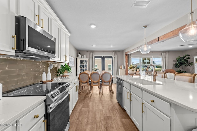 160 James Way, Southport, FL 32409 - kitchen featuring appliances with stainless steel finishes, a sink, tasteful backsplash, white cabinetry, and light wood-style flooring