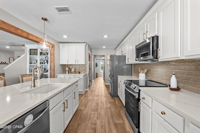 160 James Way, Southport, FL 32409 - kitchen with appliances with stainless steel finishes, a sink, white cabinetry, light wood-style flooring, and recessed lighting