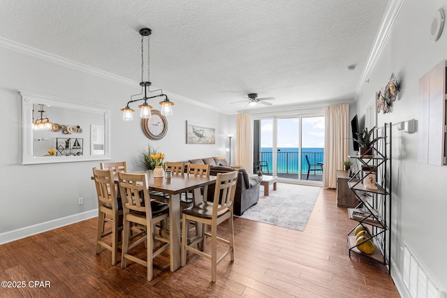 10519 Front Beach Rd Unit 1704B, Panama City Beach, FL 32407 - dining room with crown molding, a textured ceiling, ceiling fan, wood finished floors, and baseboards