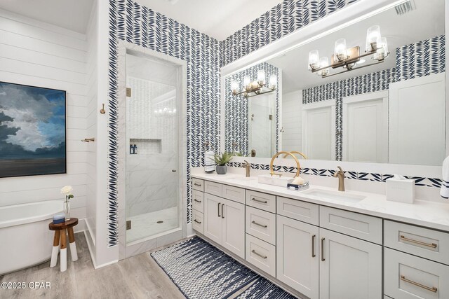135 Buddy St, Santa Rosa Beach, FL 32459 - full bath featuring a chandelier, wood finished floors, a stall shower, wallpapered walls, and double vanity
