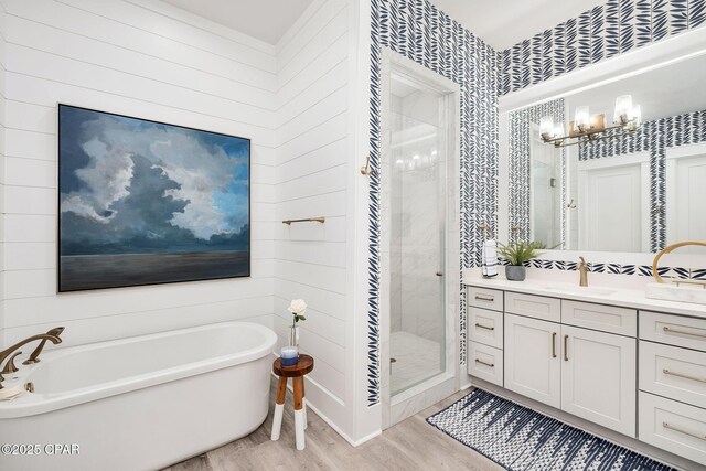 135 Buddy St, Santa Rosa Beach, FL 32459 - bathroom with wood finished floors, vanity, a soaking tub, a stall shower, and a chandelier