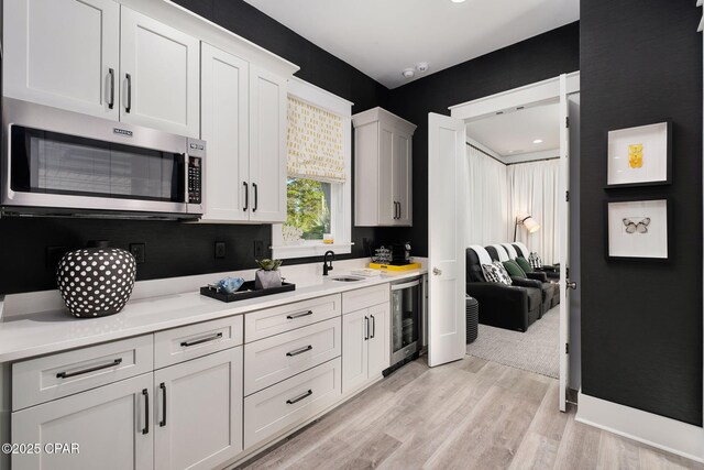 135 Buddy St, Santa Rosa Beach, FL 32459 - kitchen featuring stainless steel microwave, wine cooler, a sink, light countertops, and light wood-type flooring