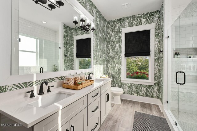 135 Buddy St, Santa Rosa Beach, FL 32459 - bathroom with wallpapered walls, wood finished floors, a shower stall, toilet, and double vanity
