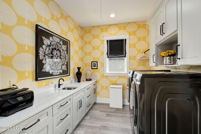 135 Buddy St, Santa Rosa Beach, FL 32459 - laundry room with wallpapered walls, washing machine and clothes dryer, light wood finished floors, cabinet space, and baseboards