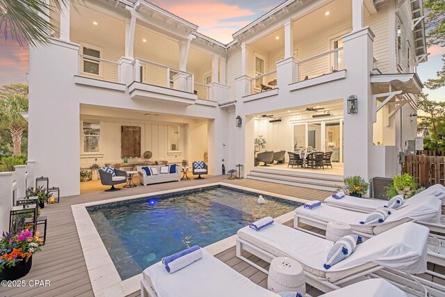 135 Buddy St, Santa Rosa Beach, FL 32459 - back of house at dusk with outdoor lounge area, a balcony, an outdoor pool, outdoor dining area, and a wooden deck