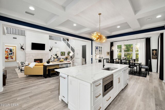 135 Buddy St, Santa Rosa Beach, FL 32459 - kitchen featuring a sink, stainless steel microwave, coffered ceiling, a center island with sink, and a lit fireplace