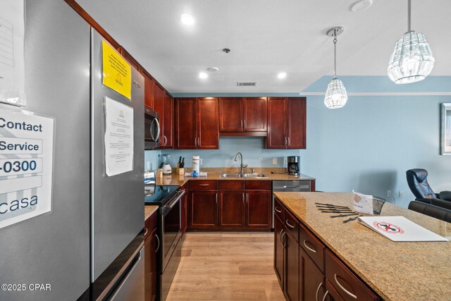 9902 S Thomas Dr Unit 135, Panama City Beach, FL 32408 - kitchen featuring appliances with stainless steel finishes, a sink, reddish brown cabinets, light wood-style floors, and decorative light fixtures