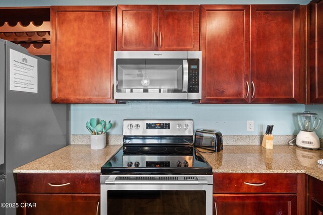 9902 S Thomas Dr Unit 135, Panama City Beach, FL 32408 - kitchen with stainless steel appliances, reddish brown cabinets, and light stone countertops